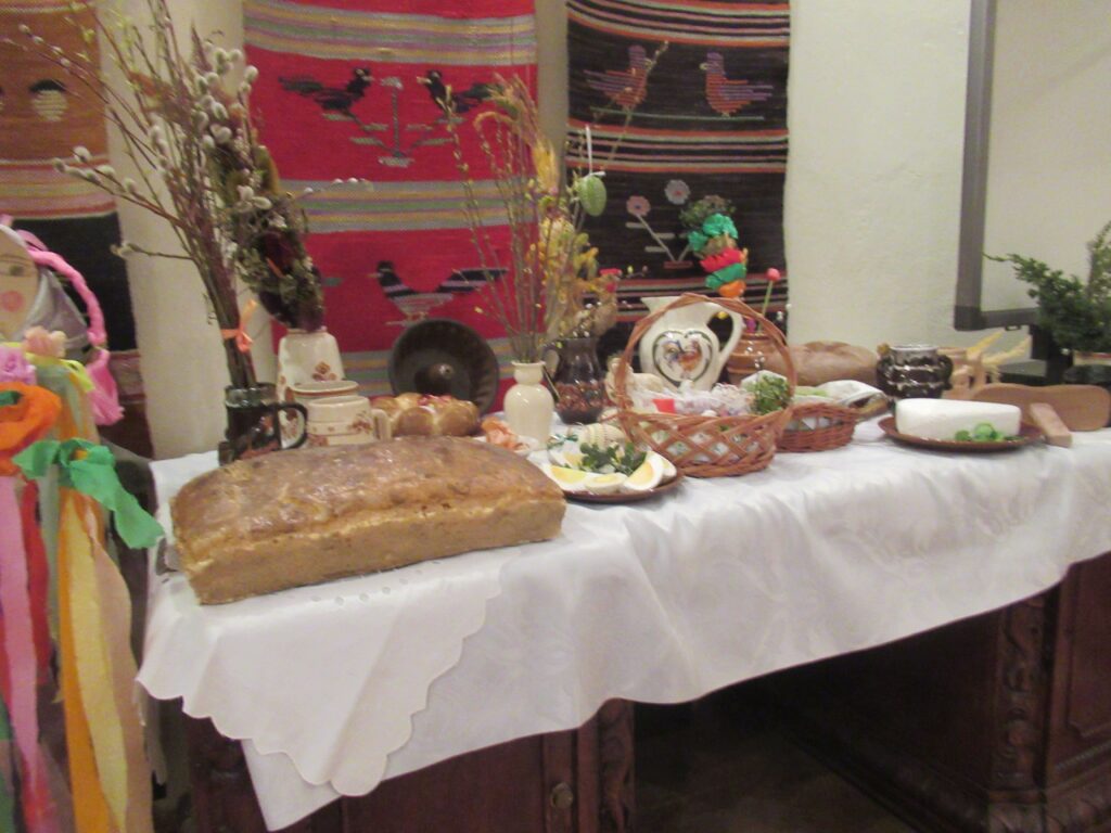 Zdjęcie stołu. Na stole są umieszczone symbole i potrawy wielkanocne.