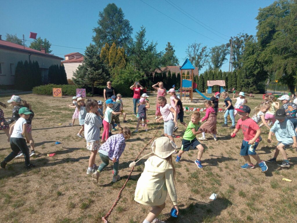 Zdjęcie przedstawia grupę dzieci wraz z paniami bawiących się na placu zabaw.