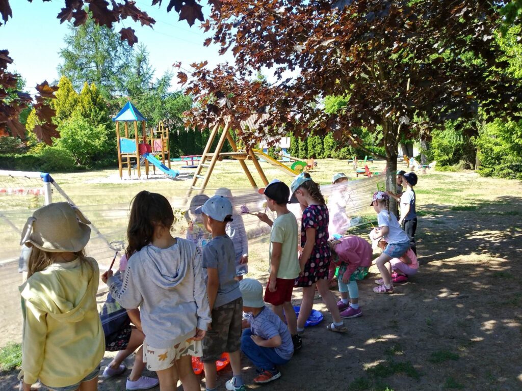 Zdjęcie przedstawia grupę dzieci bawiących się na placu zabaw.