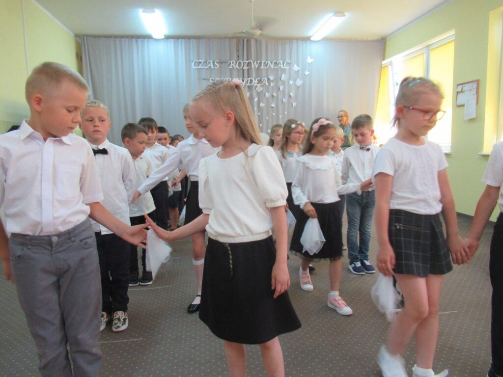 Zdjęcie przedstawia grupę tańczących dzieci w sali przedszkolnej