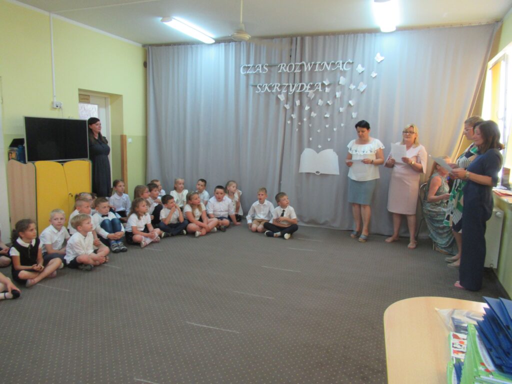 Zdjęcie przedstawia grupę dzieci i dorosłych w sali przedszkolnej