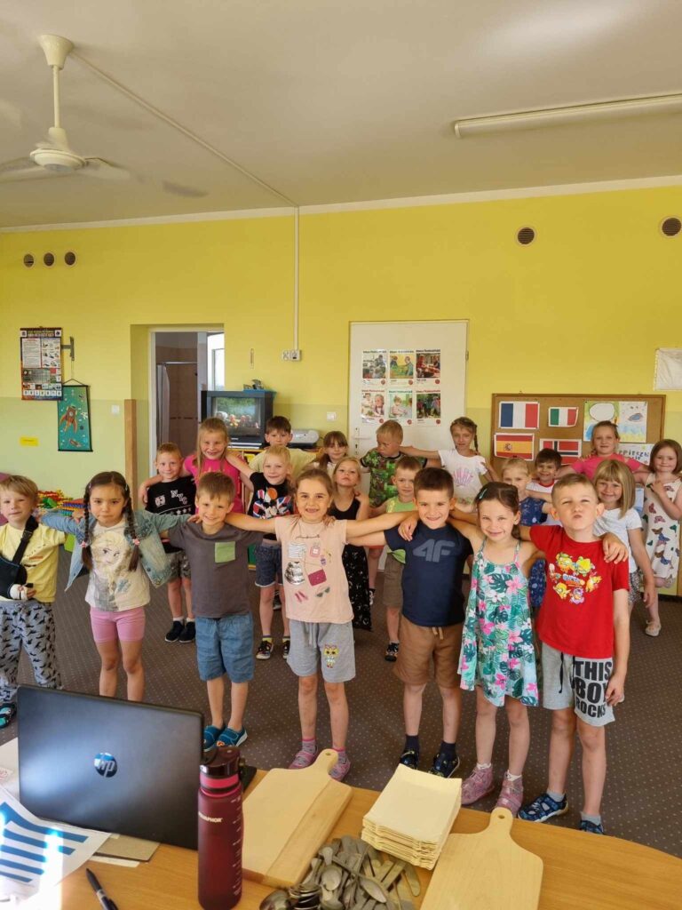 Zdjęcie przedstawia grupę tańczących dzieci w sali przedszkolnej.