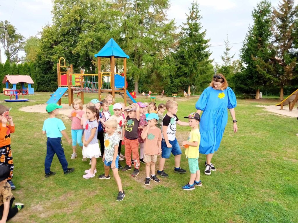 Zdjęcie przedstawia grupę ludzi bawiących się w ogrodzie przedszkolnym.