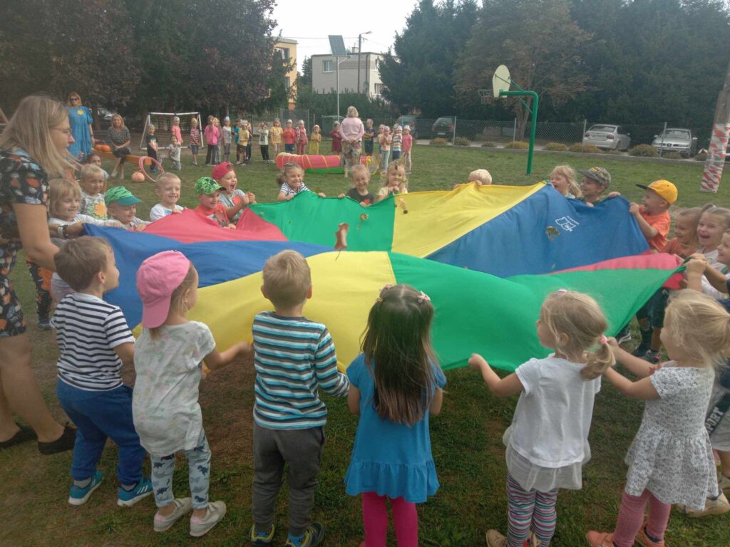 Zdjęcie przedstawia grupę ludzi bawiących się w ogrodzie przedszkolnym.