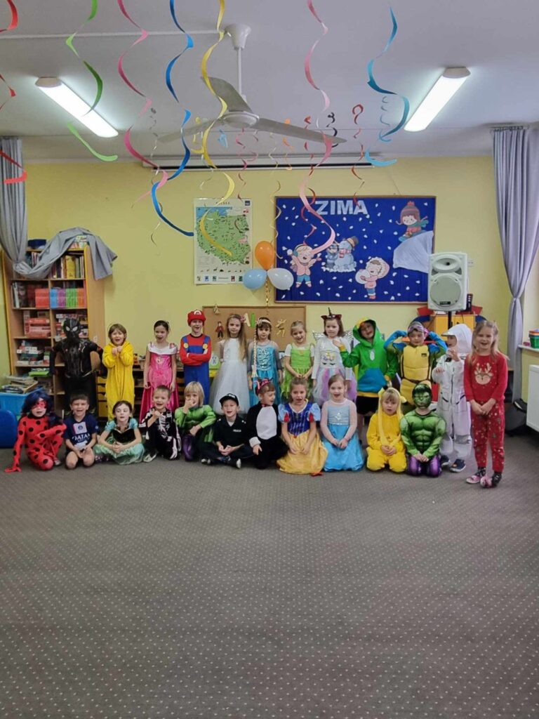 Zdjęcie przedstawia grupę dzieci w sali przedszkolnej.