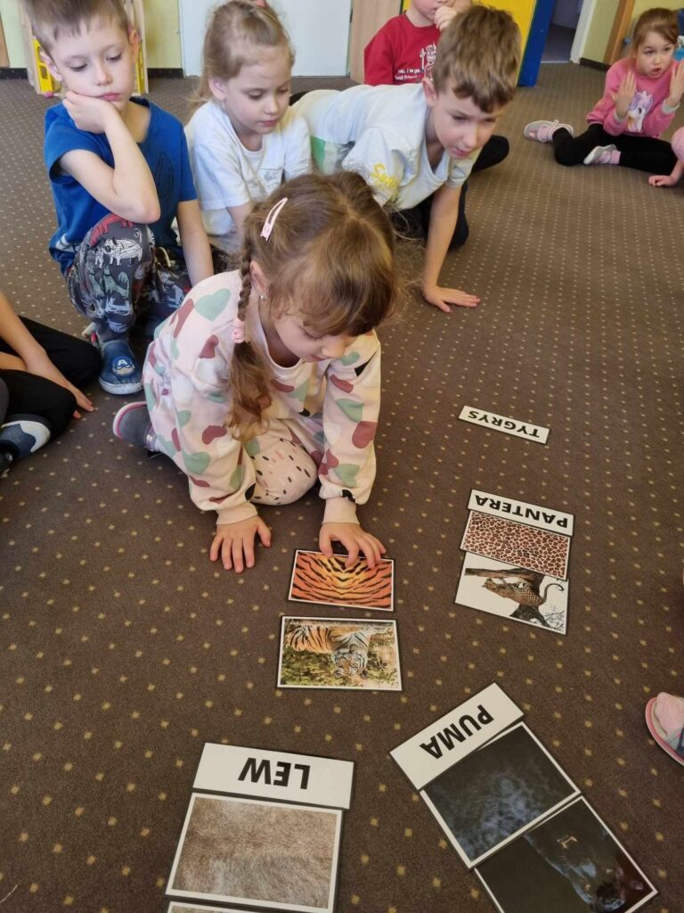 Zdjęcie przedstawia dzieci bawiące się w sali przedszkolnej.