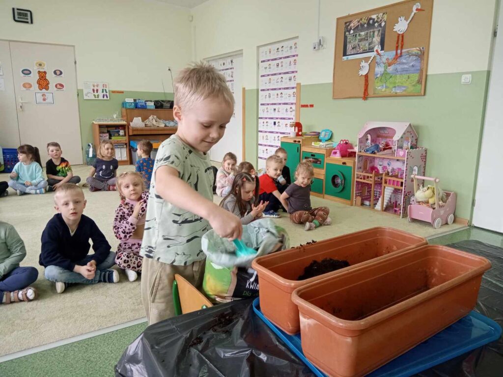 Zdjęcie przedstawia dzieci na zajęciach w sali przedszkolnej.