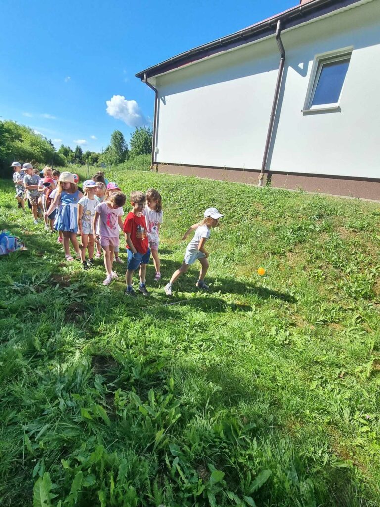 Zdjęcie przedstawia grupę dzieci w ogrodzie przedszkolnym.