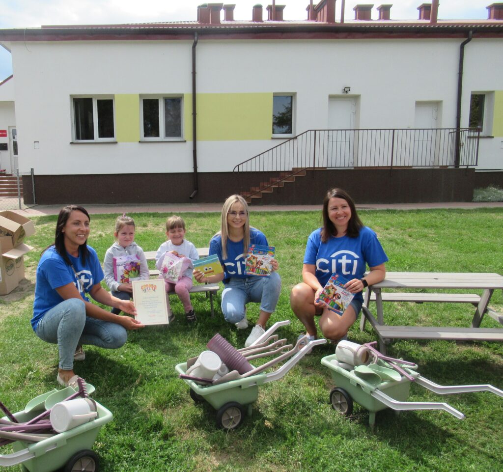 Zdjęcie przedstawia panie, dzieci oraz zabawki w ogrodzie przedszkolnym.