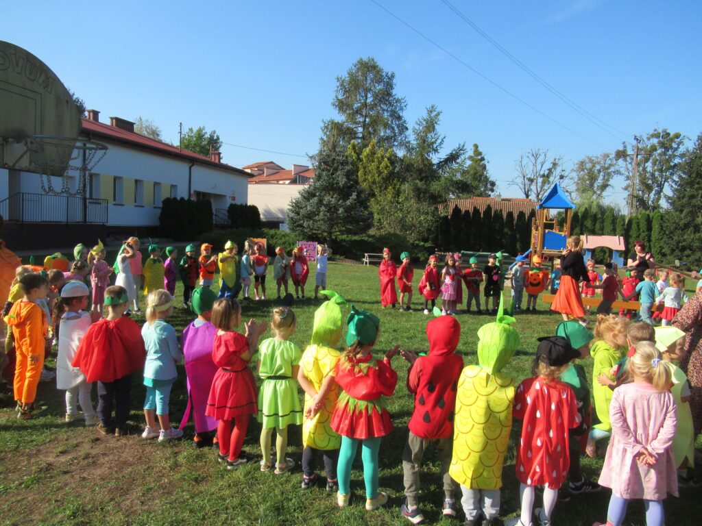 Zdjęcie przedstawia panie oraz dzieci bawiące się w ogrodzie przedszkolnym.