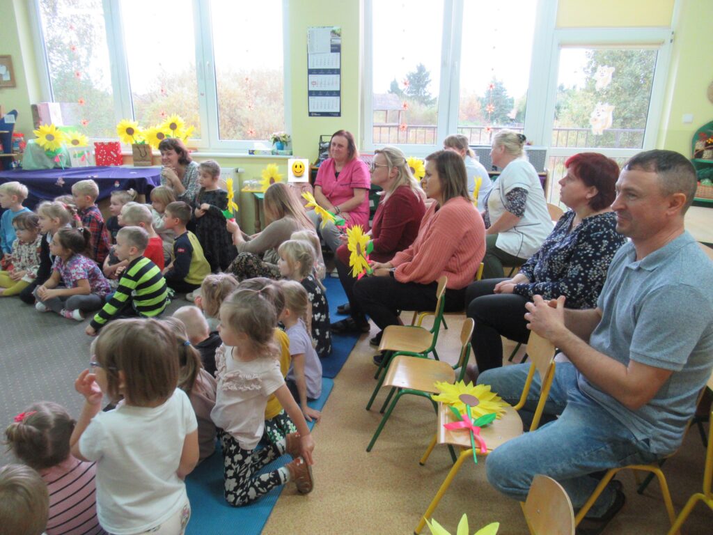 Zdjęcie przedstawia grupę ludzi w sali przedszkolnej.