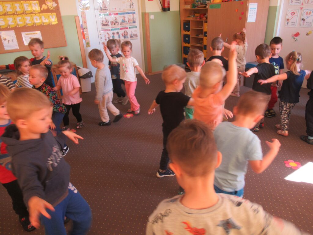 Dzieci tańczą na dywanie.