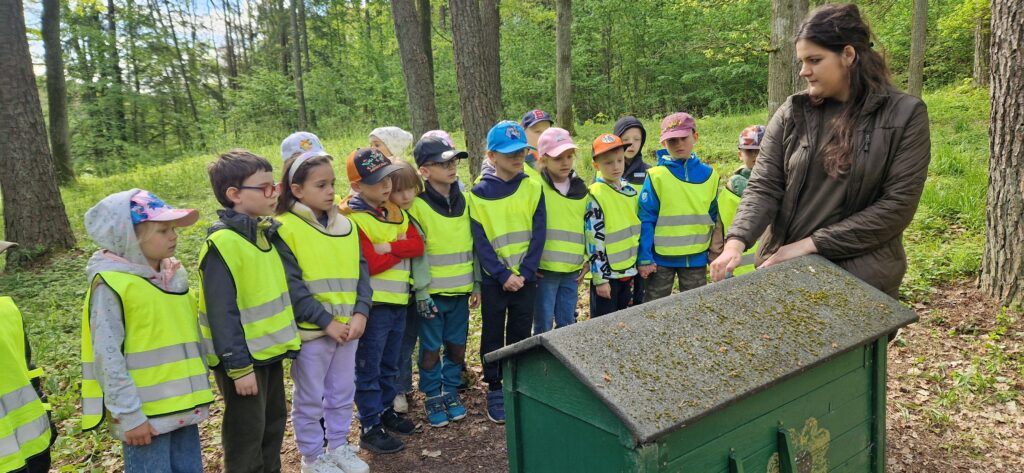 Zdjęcie przedstawia dzieci oraz przewodnika Arboretum.