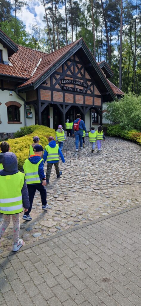 Zdjęcie przedstawia dzieci wchodzące do Leśnego Arboretum.
