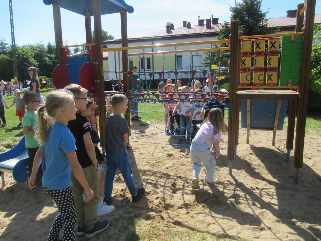 Zdjęcie przedstawia grupę bawiących się dzieci w ogrodzie przedszkolnym.