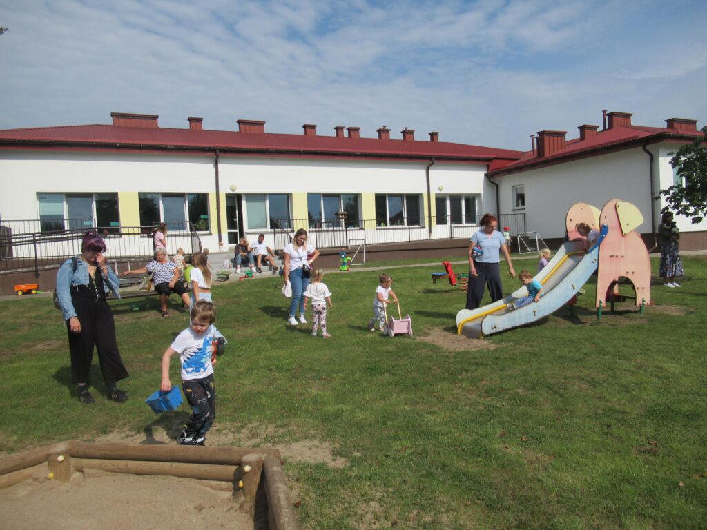 Zdjęcie przedstawia grupę ludzi w ogrodzie przedszkolnym.