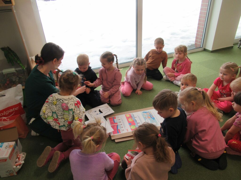 Zdjęcie przedstawia panią i dzieci w sali przedszkolnej.