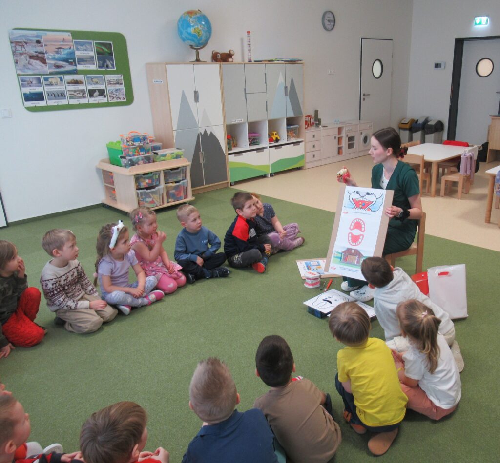 Zdjęcie przedstawia panią i dzieci w sali przedszkolnej.