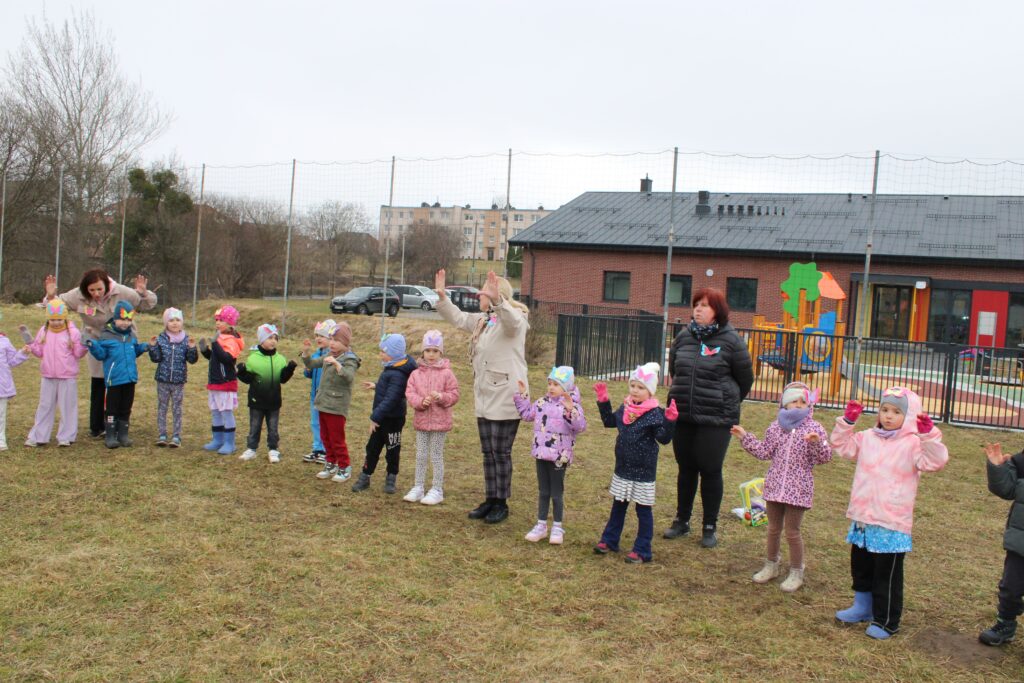 Zdjęcie przedstawia dzieci i panie na placu przedszkolnym.