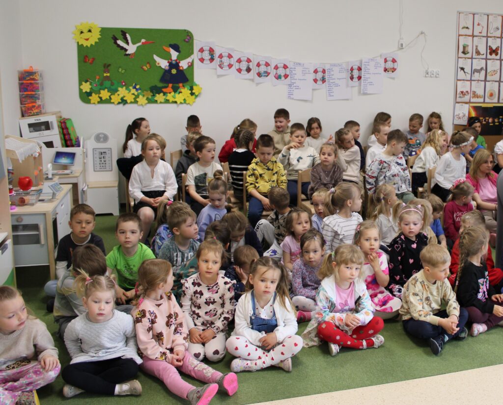 Zdjęcie przedstawia grupę ludzi w sali przedszkolnej.