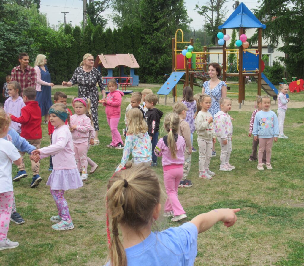 Zdjęcie przedstawia grupę bawiących się ludzi dzieci w ogrodzie przedszkolnym.