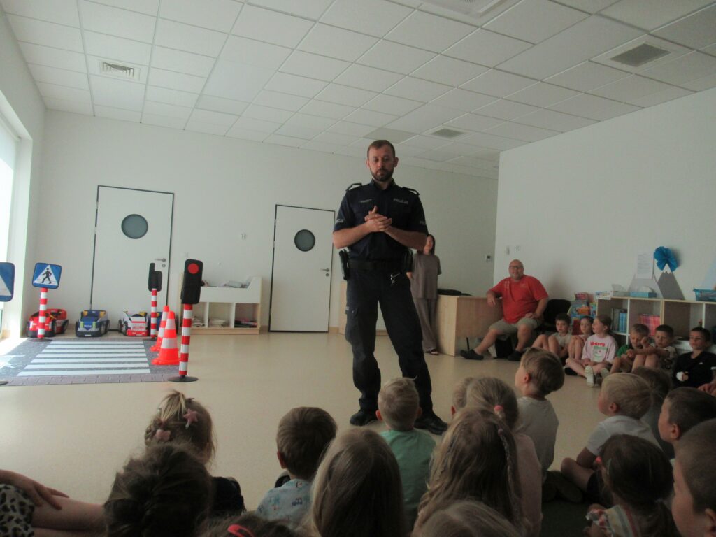 na zdjęciu policjant i dzieci siedzące na dywanie